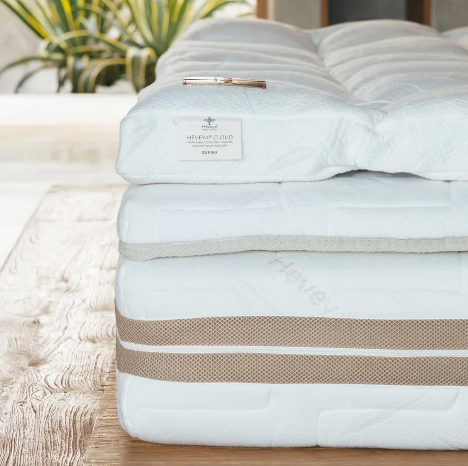 The corner of a Heveya Cloud bed close up, showing the layers stacked: the quilted down topper, the mattress beneath it and two ventilation bands along the side.